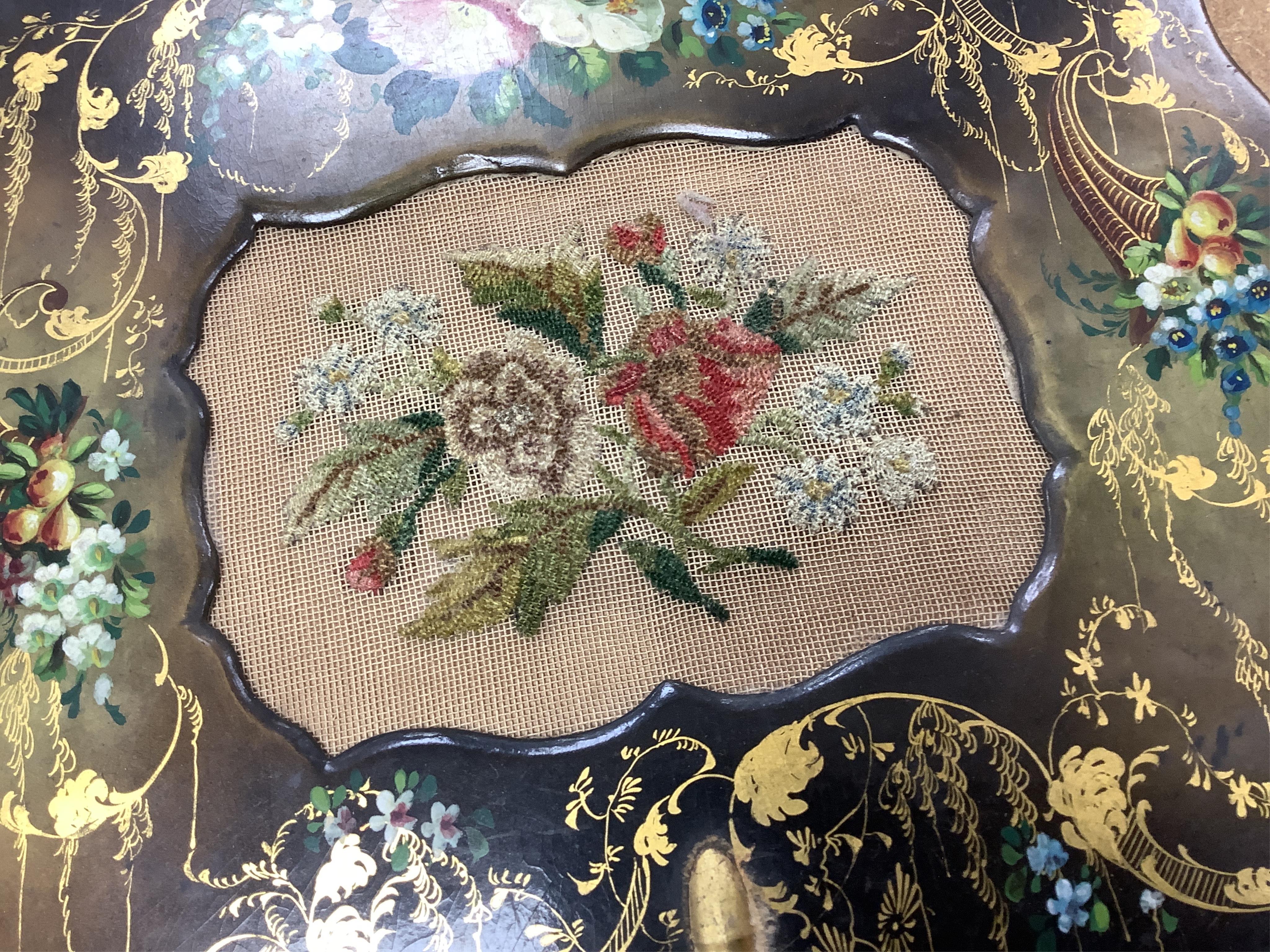 A pair of early Victorian papier maché hand screens, each with embroidered with cross stitched flowers, 41cm in length